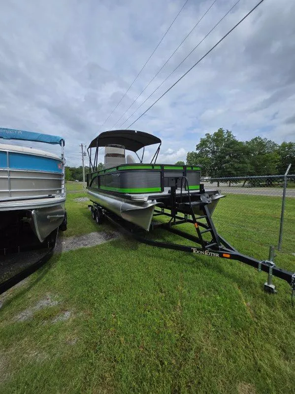 Slide: The Image of 2025 Qwest 20 XRE FISH pontoon boat on trailer, parked on grass under cloudy sky. - 1