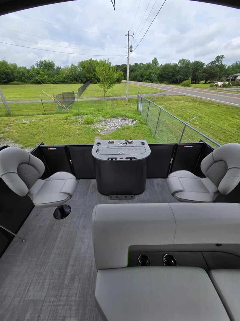 Slide: The Image of 2025 Qwest 20 XRE FISH boat interior with seating and control panel, overlooking grassy landscape. - 10