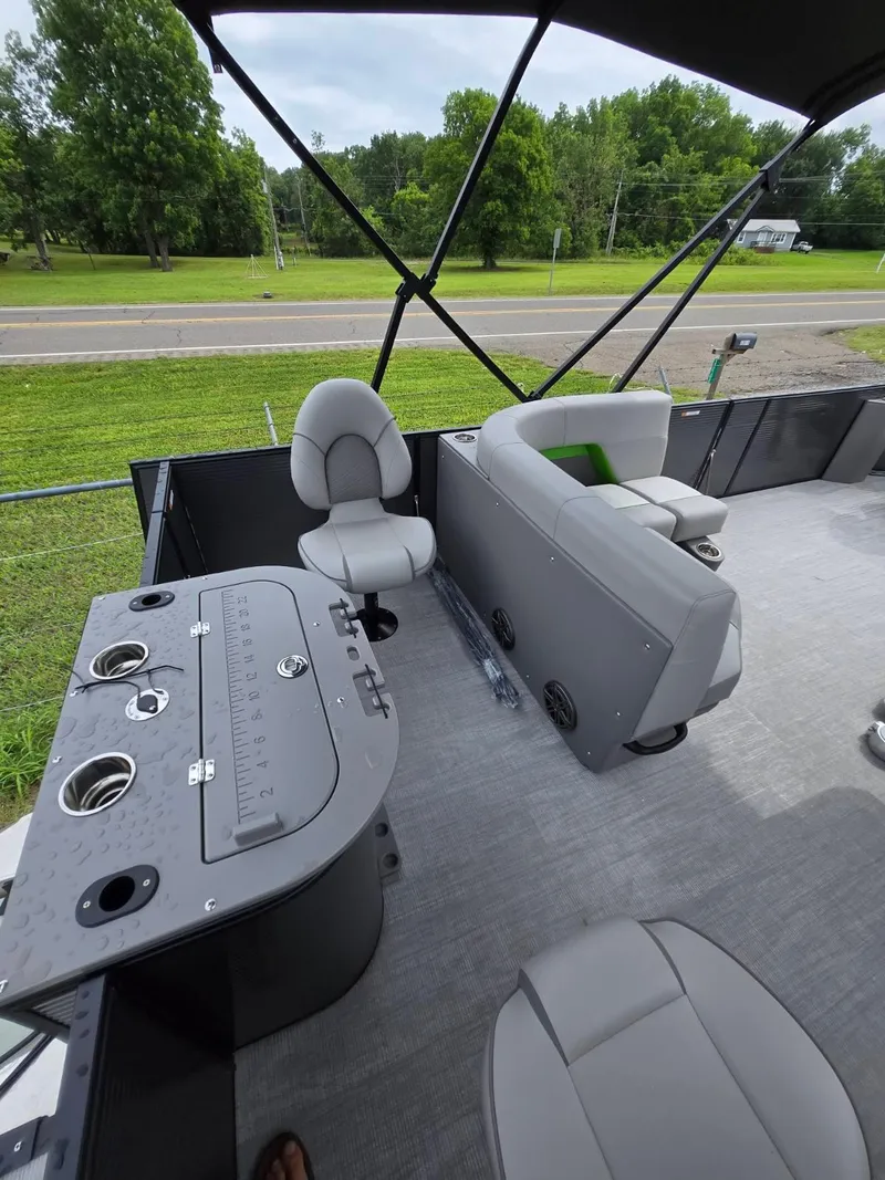 Slide: The Image of 2025 Qwest 20 XRE FISH boat interior with seating and control panel, set against a green landscape. - 11