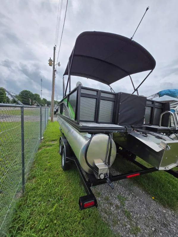 Slide: The Image of 2025 Qwest 20 XRE FISH pontoon boat with canopy, parked on grass near a fence. - 3