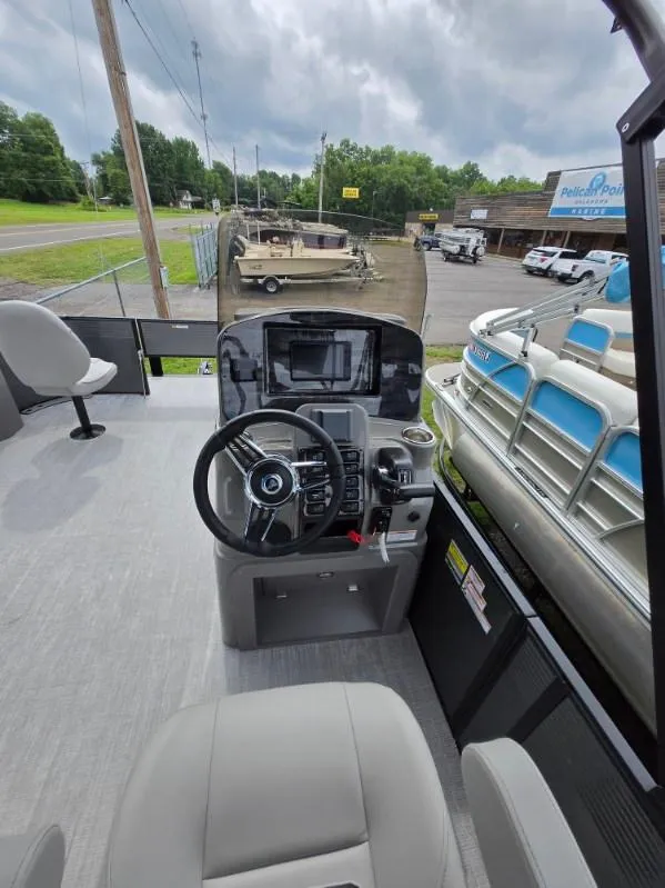 Slide: The Image of 2025 Qwest 20 XRE FISH boat interior with steering console and seating, parked outdoors. - 8