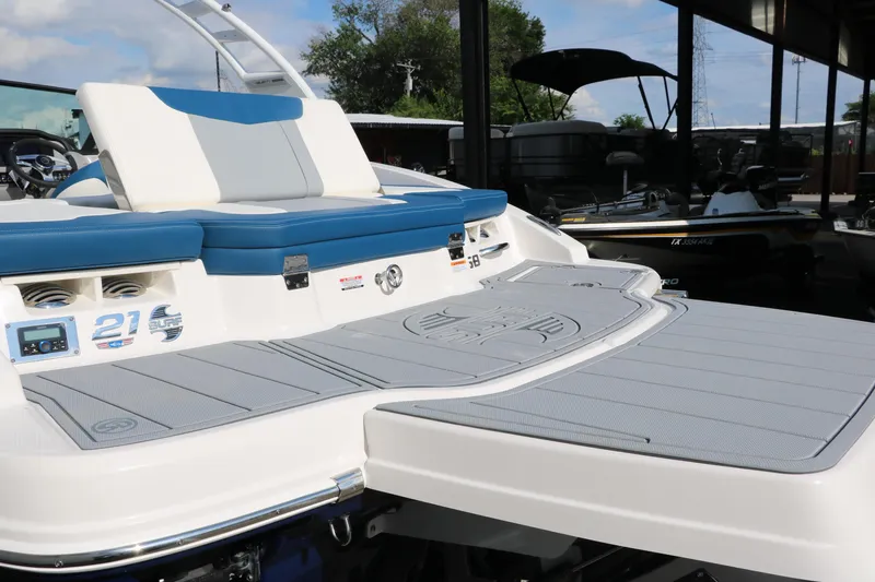 Slide: The Image of 2025 Chaparral 21 Surf boat with blue and white seating, docked outdoors. - 32