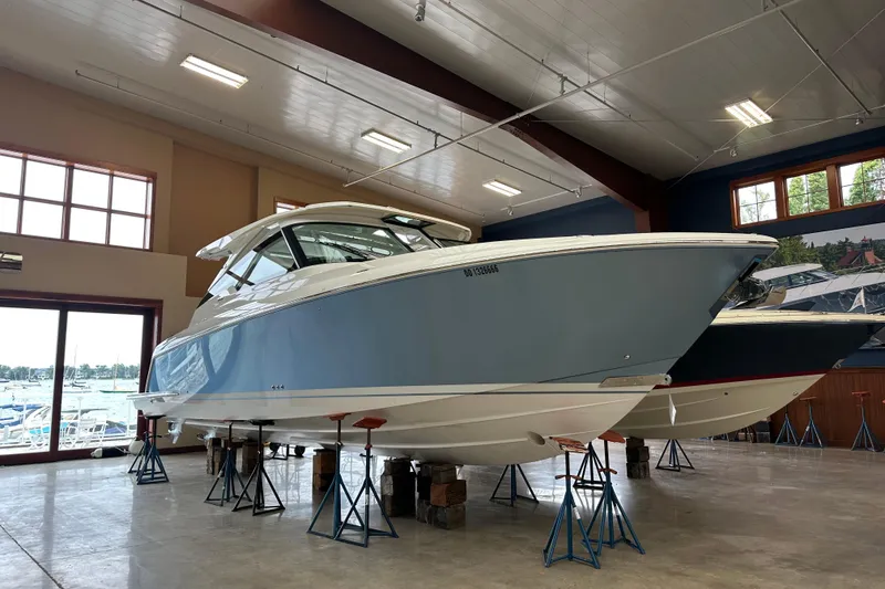 Slide: The Image of 2022 Tiara Yachts 38 LX in showroom, elevated on stands, with large windows in background. - 10