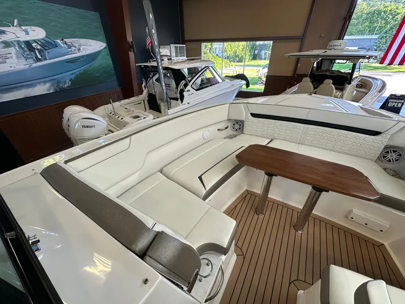 Slide: The Image of 2022 Tiara Yachts 38 LX interior with elegant seating and wooden table in showroom. - 19