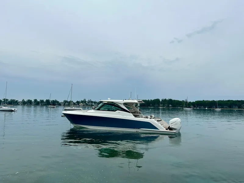 Slide: The Image of 2022 Tiara Yachts 38 LX on calm water, surrounded by sailboats and trees. - 5