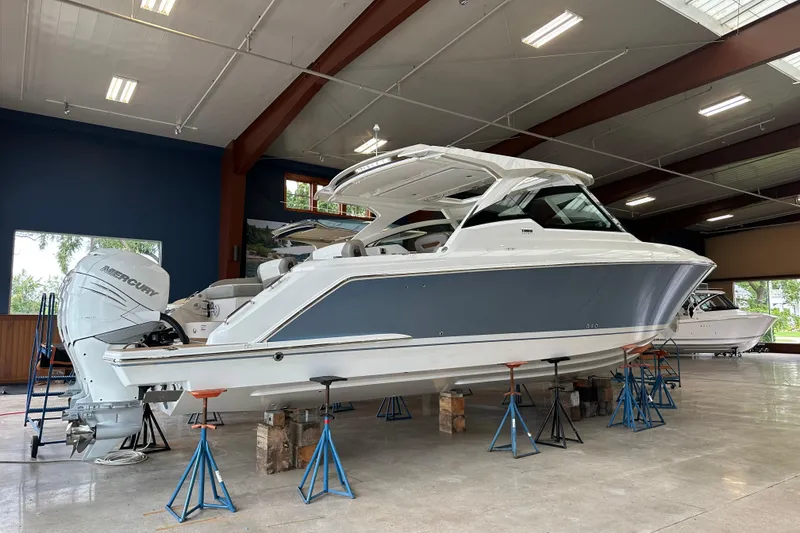 Slide: The Image of 2022 Tiara Yachts 38 LX in showroom, elevated on stands, with Mercury outboard engines. - 9