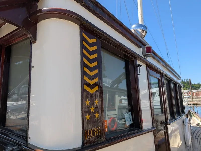 Slide: The Image of Classic 1936 Motorsailer with wooden details docked at marina under clear blue sky. - 12