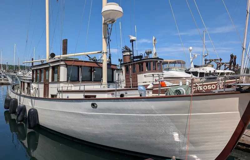 Slide: The Image of Classic 1936 Motorsailer docked at marina, featuring wooden hull and masts under clear blue sky. - 2
