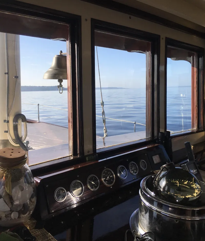 Slide: The Image of Classic 1936 motorsailer interior with ocean view through windows, featuring nautical instruments and bell. - 24