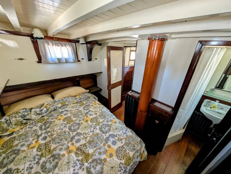 Slide: The Image of 1936 Classic Motorsailer cabin interior with bed, wooden beams, and small bathroom. - 30