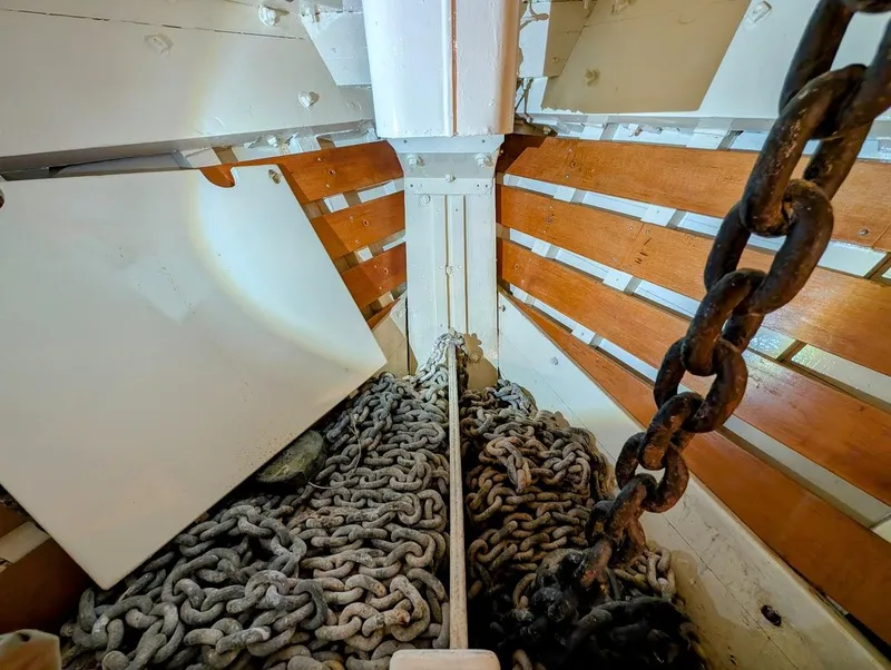 Slide: The Image of Anchor chain storage in 1936 Classic Motorsailer boat, featuring wooden slats and metal chains. - 36