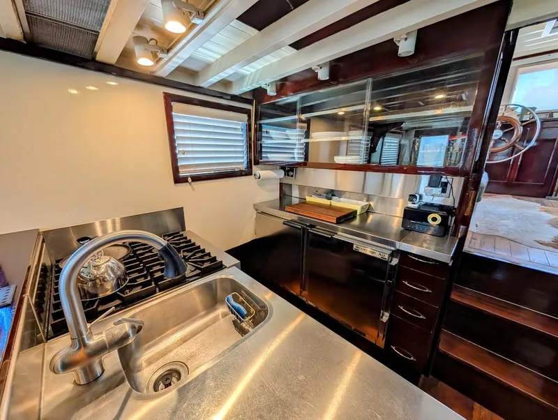 Slide: The Image of 1936 Classic Motorsailer kitchen with stainless steel sink, stove, and wooden cabinetry. - 38