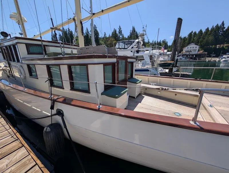 Slide: The Image of Classic 1936 Motorsailer docked at marina with scenic forest backdrop. - 4