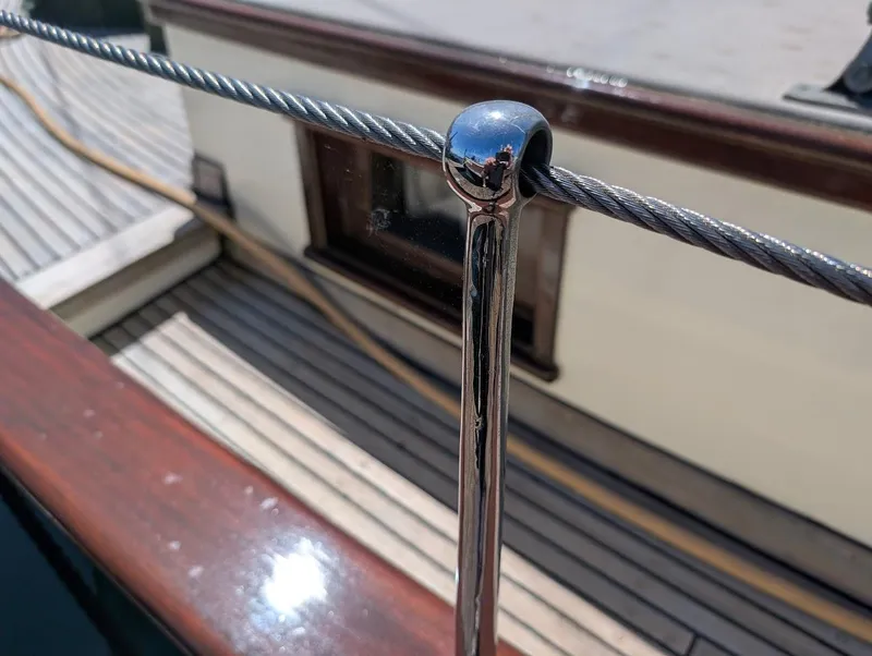 Slide: The Image of Polished metal railing on 1936 Classic Motorsailer, with wooden deck and cabin detail. - 8