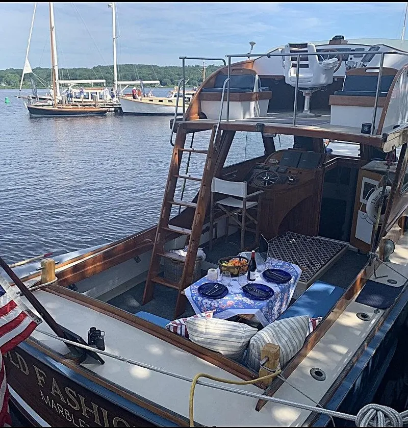 Slide: The Image of 1959 Goudy & Stevens Flybridge Cruiser docked, featuring a cozy dining setup on deck. - 11