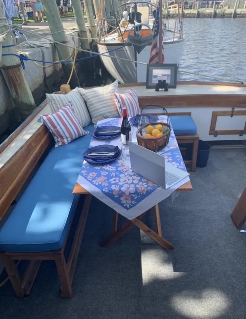 Slide: The Image of 1959 Goudy & Stevens Flybridge Cruiser with cozy dining setup, blue cushions, and nautical decor. - 12
