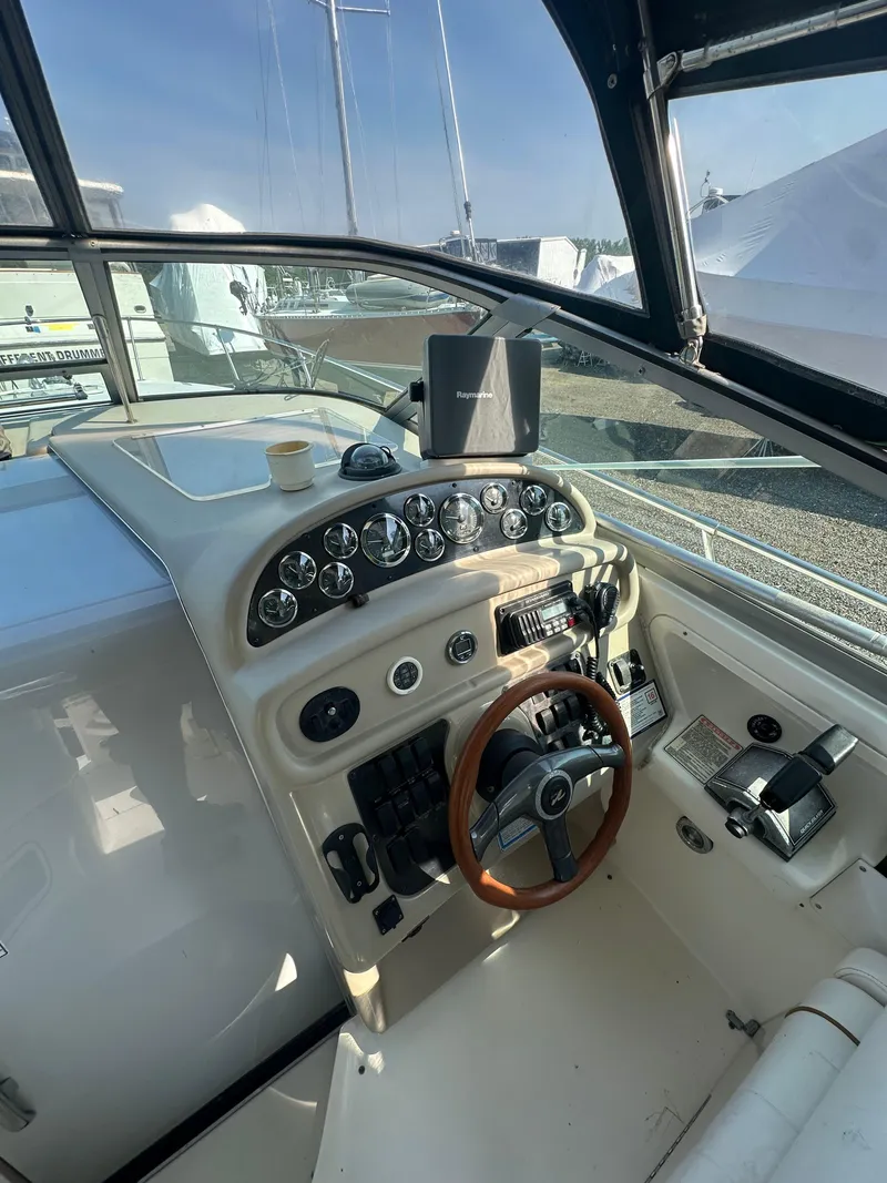 Slide: The Image of 1998 Sea Ray 290 Sundancer helm with gauges, steering wheel, and navigation equipment. - 12