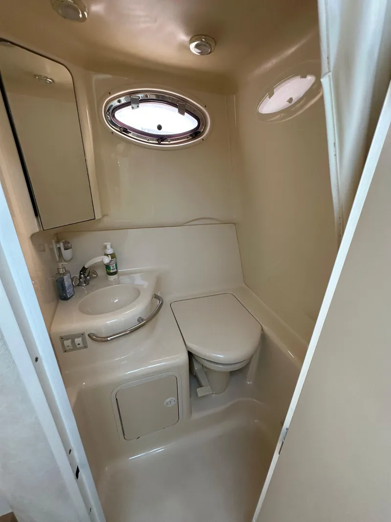 Slide: The Image of 1998 Sea Ray 290 Sundancer bathroom with sink, toilet, and porthole window. - 22