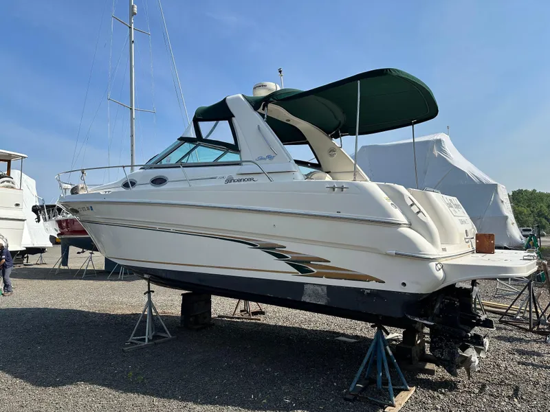 Slide: The Image of 1998 Sea Ray 290 Sundancer boat on stands, white hull, green canopy, outdoor storage. - 3