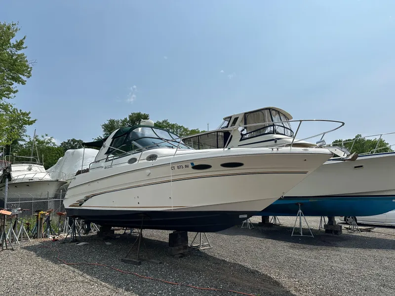 Slide: The Image of 1998 Sea Ray 290 Sundancer boat on dry dock, surrounded by other vessels. - 5