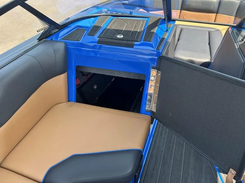 Slide: The Image of 2025 Moomba Tykon boat interior with blue and tan seating, open storage compartment. - 12