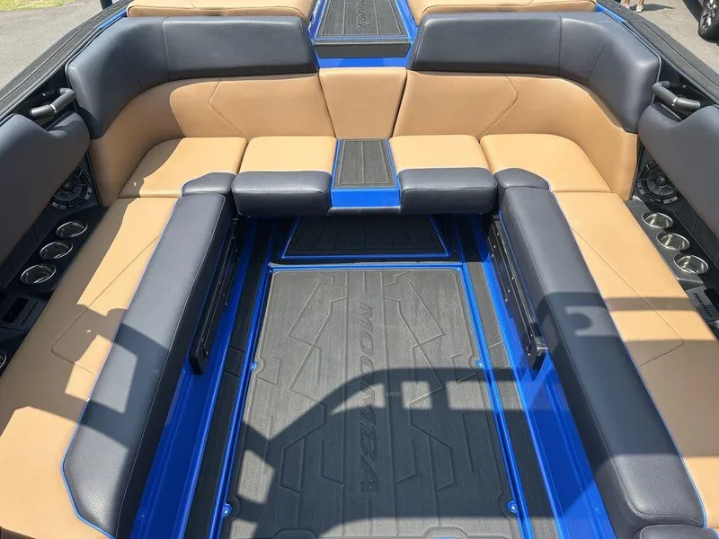 Slide: The Image of 2025 Moomba Tykon boat interior with tan and black seating, blue accents, and cup holders. - 29