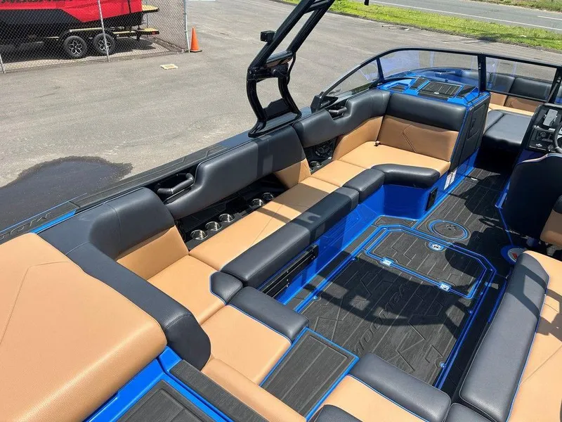 Slide: The Image of 2025 Moomba Tykon boat interior with tan and black seating, blue accents, and cup holders. - 31
