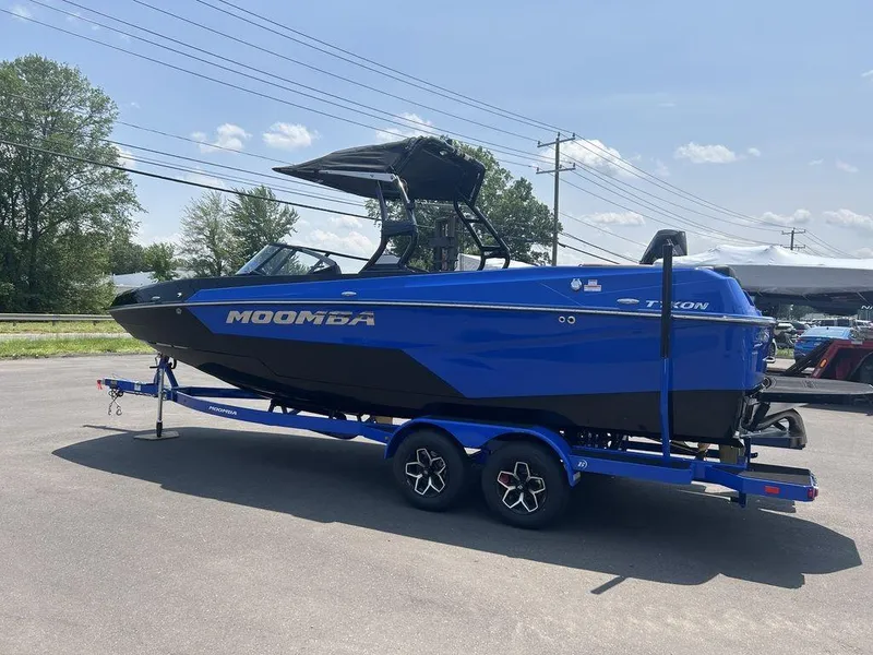 Slide: The Image of 2025 Moomba Tykon boat in blue on a trailer, parked outdoors. - 32