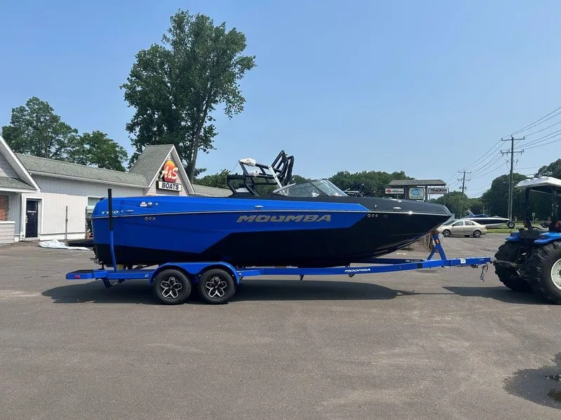 Slide: The Image of 2025 Moomba Tykon boat on trailer, parked outdoors, blue and black design. - 33