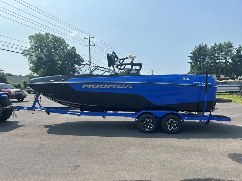 Slide: The Image of 2025 Moomba Tykon boat on trailer, blue and black design, parked outdoors. - 35