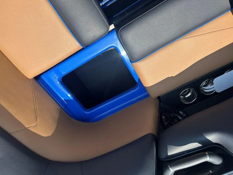 Slide: The Image of 2025 Moomba Tykon interior with blue and brown seating, cup holders, and storage compartment. - 5