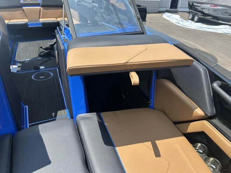Slide: The Image of 2025 Moomba Tykon boat interior with tan and black seating, blue accents, and cup holders. - 8