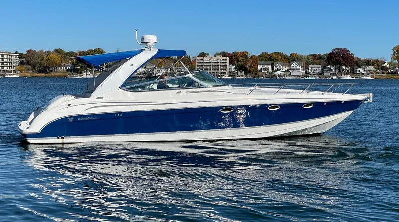 The Image of 2003 Formula 370 SS boat on calm water, blue and white design, clear sky background. - 0