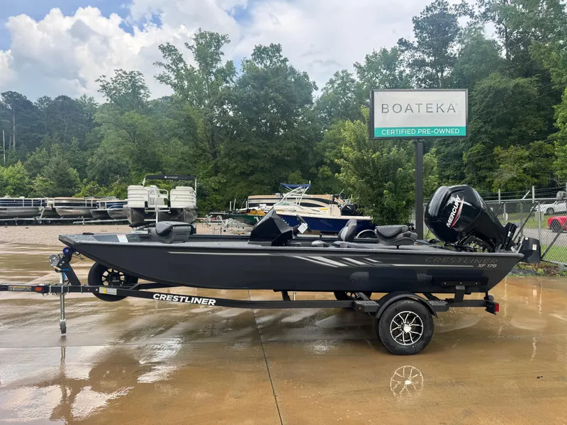 The Image of 2025 Crestliner XF 179 boat on trailer at Boateka dealership, surrounded by trees. - 0