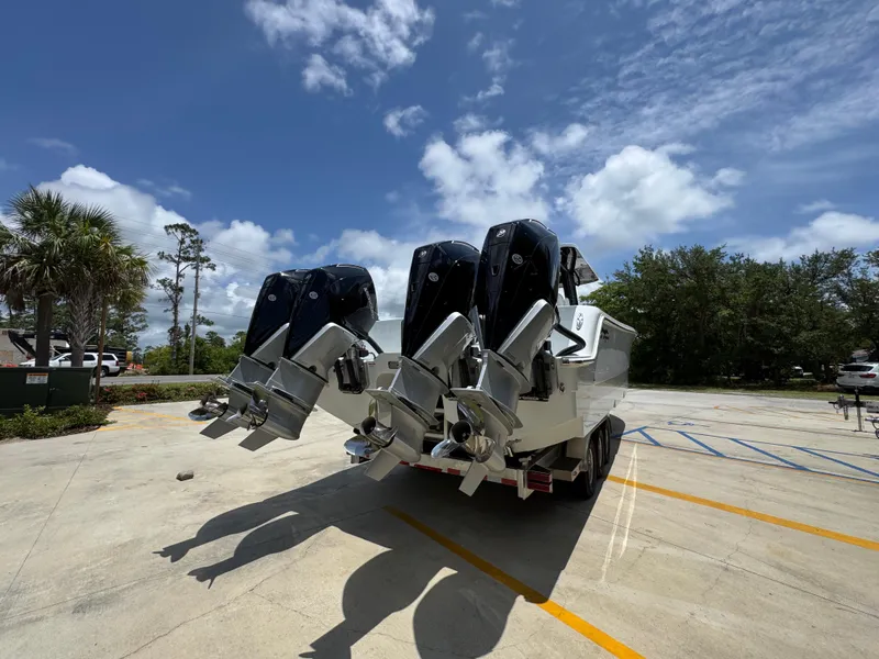 Slide: The Image of 2026 Invincible 36 Catamaran with triple outboard engines in a sunny parking lot. - 13