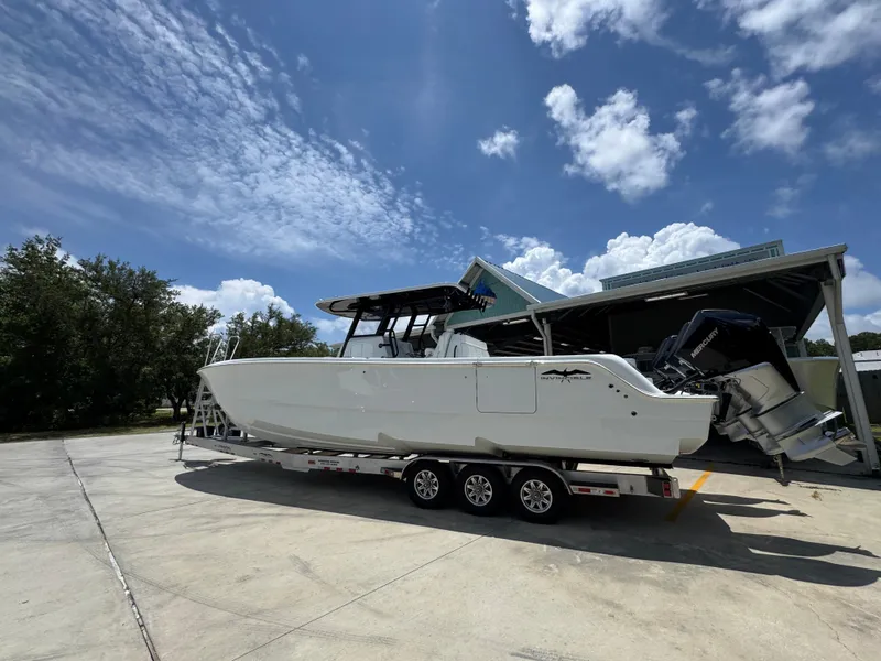 Slide: The Image of 2026 Invincible 36 Catamaran on trailer under blue sky, parked near a building. - 18