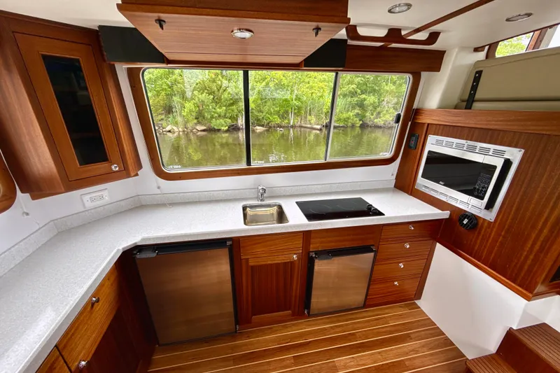 Slide: The Image of 2023 Nordic Tug 34 interior kitchen with modern appliances and scenic window view. - 15