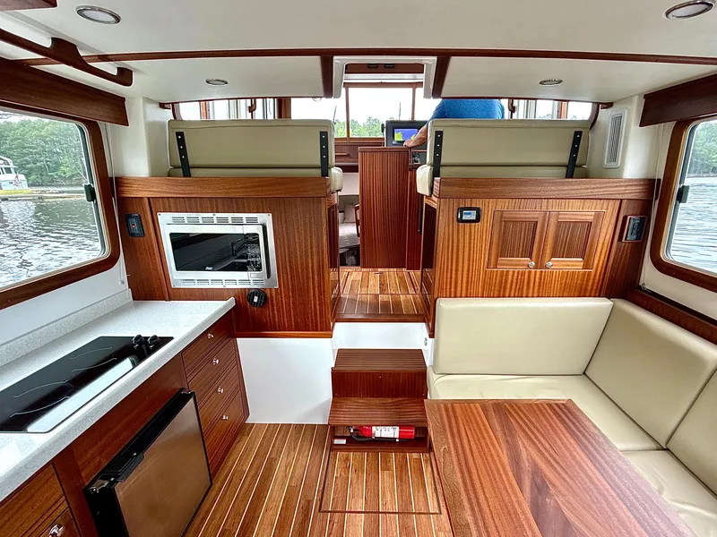 Slide: The Image of Interior of 2023 Nordic Tug 34, featuring wood finishes, seating, and kitchen area. - 17