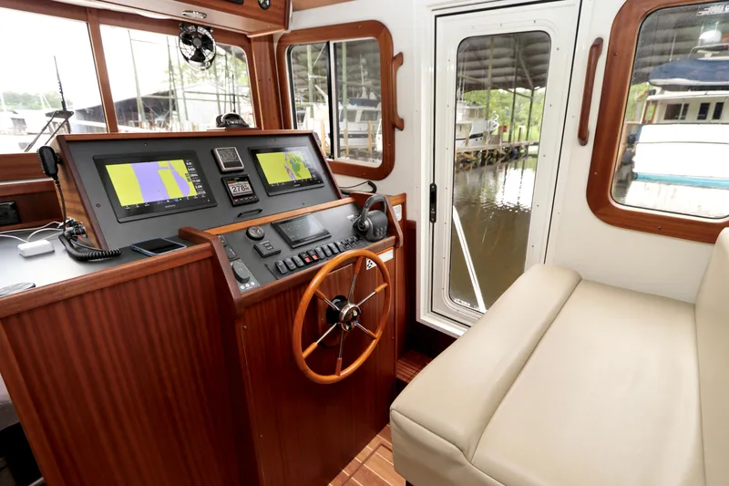 Slide: The Image of 2023 Nordic Tug 34 Tug helm with navigation screens and wooden steering wheel. - 21