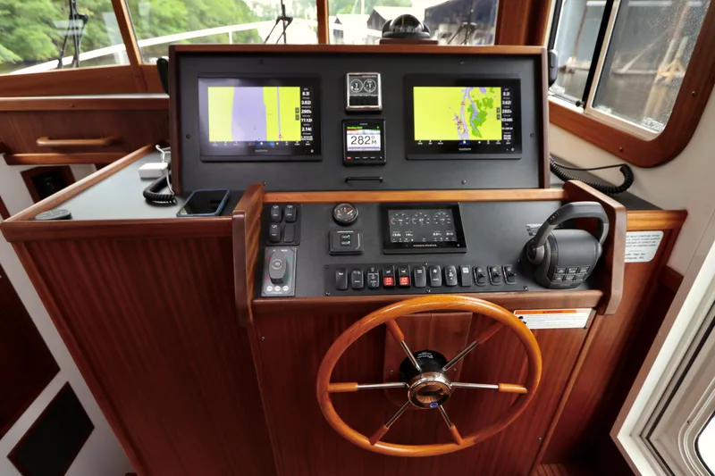 Slide: The Image of 2023 Nordic Tug 34 Tug helm with dual navigation screens and wooden steering wheel. - 22
