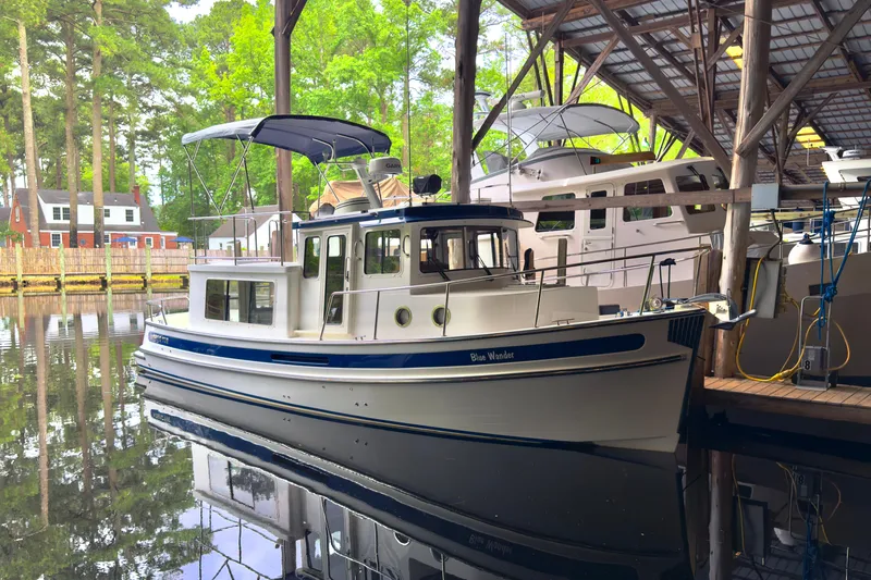 Slide: The Image of 2023 Nordic Tug 34 docked in a serene marina setting. - 27