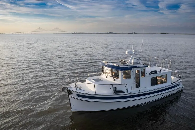 Slide: The Image of 2023 Nordic Tug 34 Tug on calm water with bridge in background. - 28
