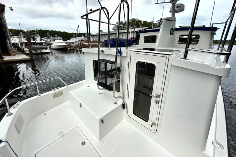 Slide: The Image of 2023 Nordic Tug 34 docked, showcasing rear deck and cabin entrance. - 5