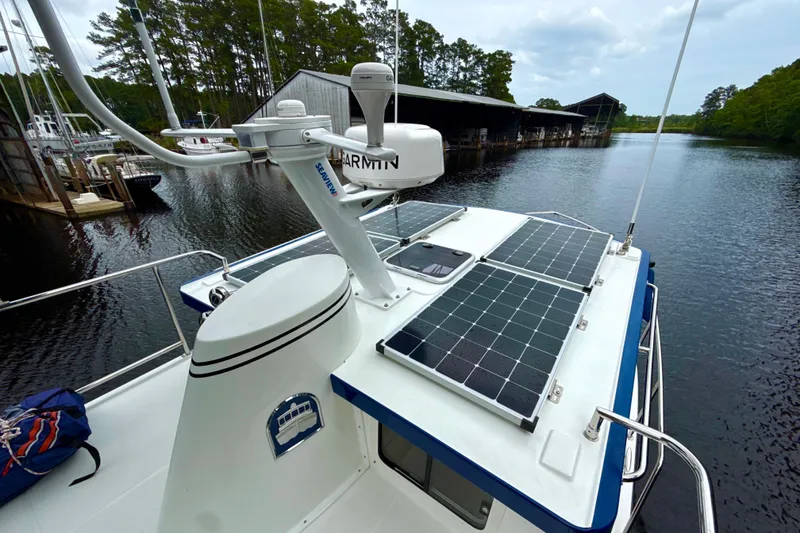 Slide: The Image of 2023 Nordic Tug 34 with solar panels on deck, docked by a serene marina. - 8