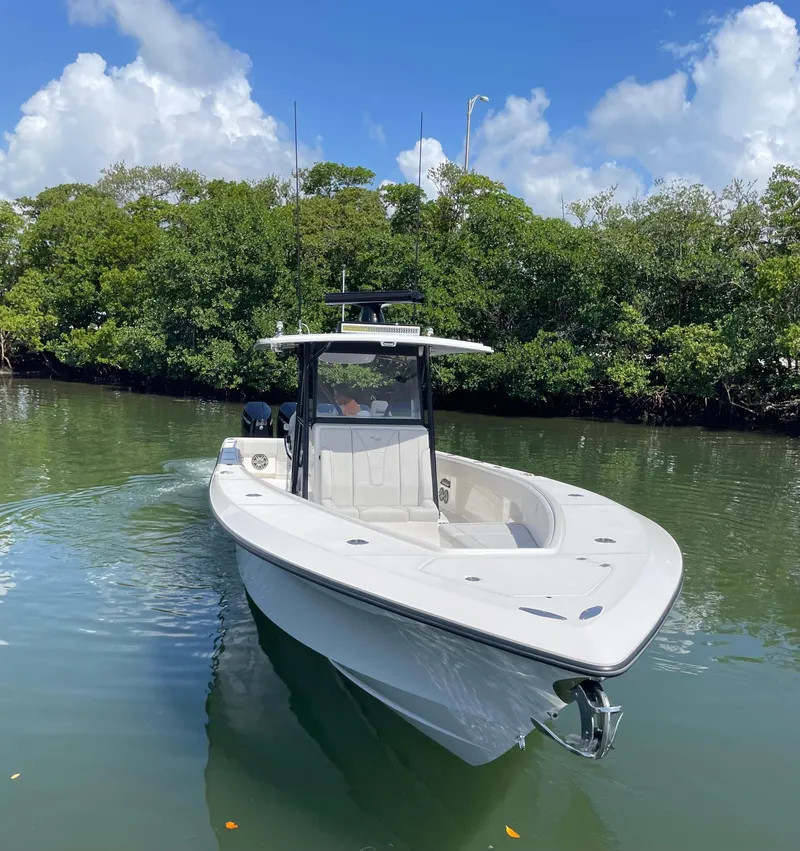 Slide: The Image of 2024 SeaVee 390Z boat on calm water, surrounded by lush greenery and blue sky. - 2