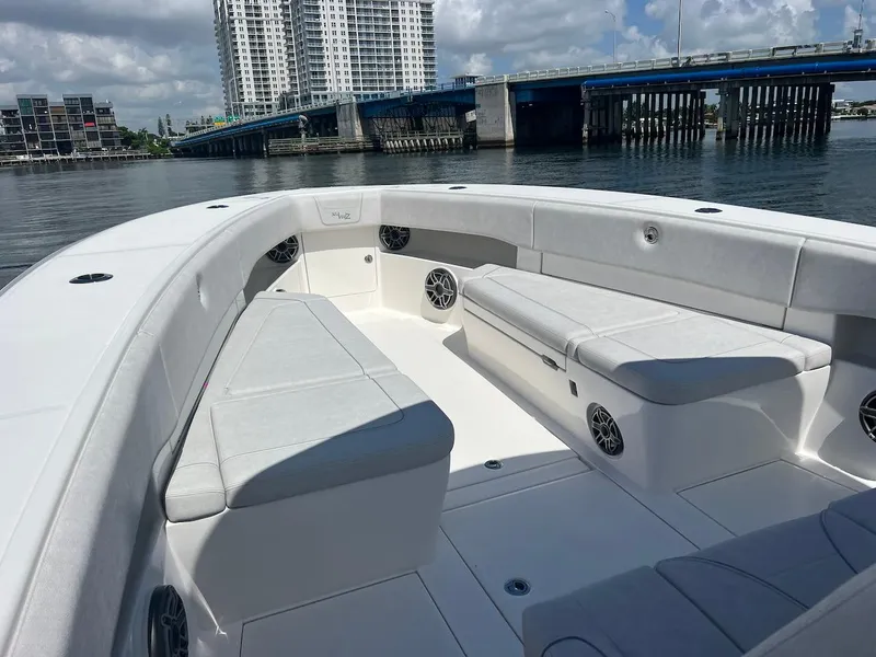 Slide: The Image of 2024 SeaVee 390Z boat interior with spacious seating, docked near a bridge and cityscape. - 8