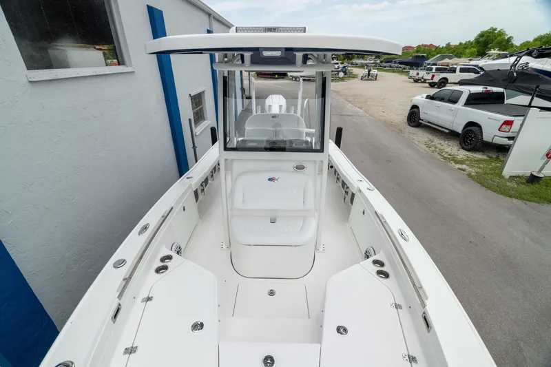 Slide: The Image of 2026 Crevalle 24 HCO boat, white deck, center console, parked near building and vehicles. - 35