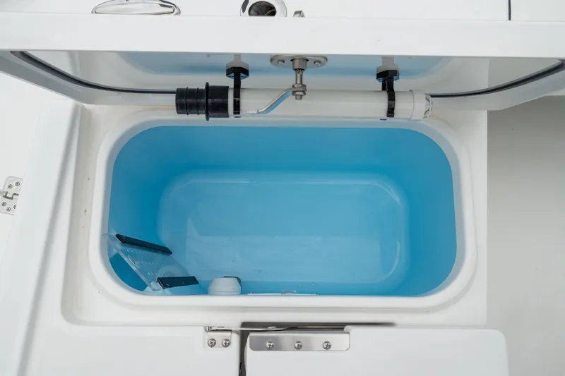Slide: The Image of Livewell compartment in 2026 Crevalle 24 HCO boat, featuring plumbing and blue interior. - 8