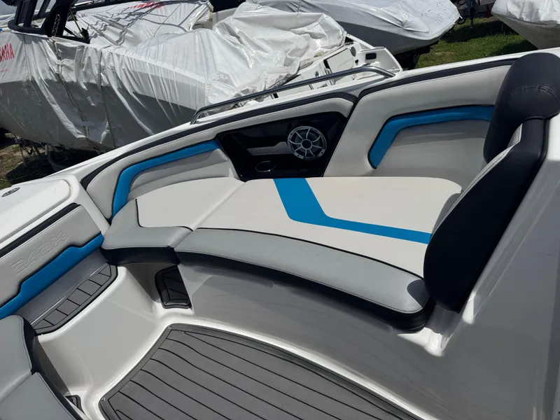 Slide: The Image of 2018 Yamaha Boats 242X E-Series interior with blue and gray seating, speaker, and covered boats nearby. - 13