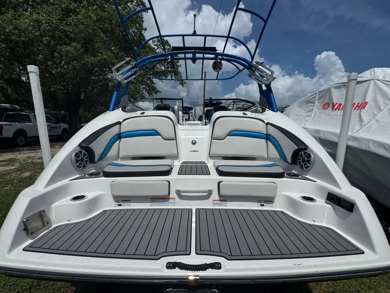Slide: The Image of 2018 Yamaha Boats 242X E-Series, rear view, showcasing seating and deck, under a blue sky. - 3